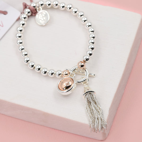 Beaded bracelet with orb and tassel charms and T bar clasp