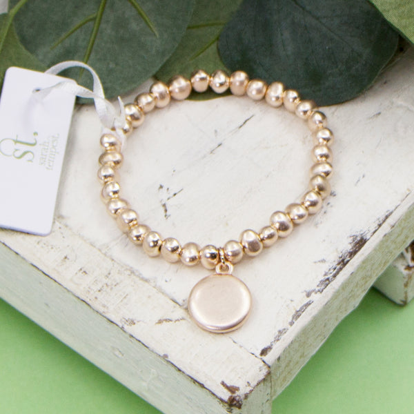 Worn rose gold stretchy beaded bracelet with little disc charm