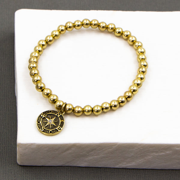 Stretchy beaded bracelet with wanderlust and compass double sided charm
